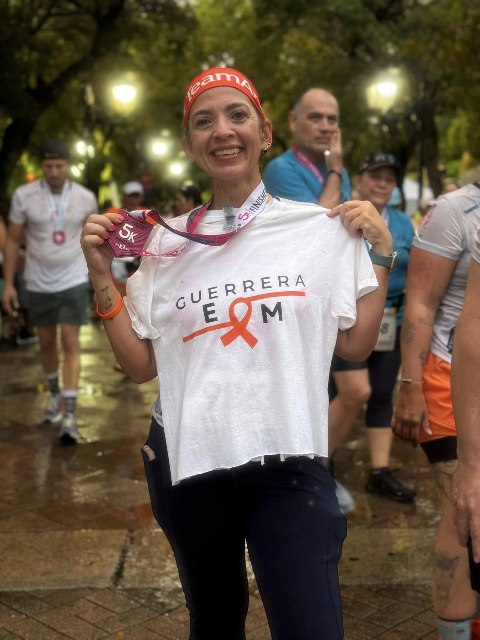 Corredora con camiseta de Guerrera EM mostrando su medalla de 5K tras la carrera